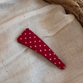 Vue détaillée de la pince à cheveux en tissu rouge à pois blancs sur fond de lin beige - Style Triangle Mince / Rouge à Pois