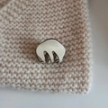 Close-up of a small cream acetate hair claw with black trim on a beige knit fabric texture - Cloud Small Claw-Cream White