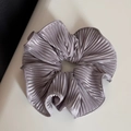 Detailed view of silver pleated satin scrunchie with metallic sheen and elastic texture - Purple