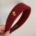Dettaglio macro del cerchietto in lana rosso vino con ornamento in metallo dorato - Rosso