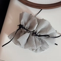 Vue détaillée du chouchou en mousseline à pois blancs avec un nœud en ruban noir - Style à Volants et Pois