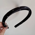 Detailaufnahme eines dicken schwarzen Satin-Haarreifens mit minimalistischem weißen Blumenmuster - Floral Satin Stirnband - Schmal / Schwarz