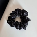 Nahaufnahme eines schwarzen Blumen-Satin-Scrunchie mit glatter Seidentextur und Falten - Floral Satin Haargummi / Schwarz