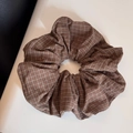 Vue détaillée d'un grand chouchou à carreaux marron avec des motifs blancs et orange - Élastique à cheveux / Marron