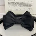 Elegant large black satin double-layered bow hair claw clip on a minimalist white ceramic plate - Runaway Princess Bun Clip