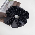 Close-up of black velvet and satin scrunchie with a Made in Korea woven label - Black
