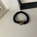 Primer plano detallado de un coletero plisado negro con una cuenta decorativa color ámbar - Negro-Cuenta Redonda