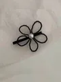 Dettaglio di un fermaglio floreale con perline nere e un grande ornamento di perla bianca - Fiore nero