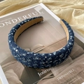 Dettaglio del cerchietto in denim blu scuro con paillettes argento su una rivista - Blu scuro