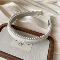 Detailed close-up of cream jacquard headband with pearls on a satin background - White