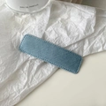 Detailed view of light blue denim fabric hair clip with fine stitching on white paper - Light Blue
