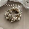 Élastique à cheveux élégant avec perles et cristaux sur un magazine, éclairage doux - Champagne