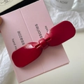 Dettaglio di un fermaglio per capelli a fiocco rosso acceso su scheda rosa decorativa - Rosso