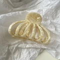 Gros plan d'une pince à cheveux en acétate crème avec texture marbrée sur papier - Blanc Cassé