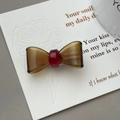 Detailed macro of translucent acetate bow hair clip with gold France Handmade lettering - Earthy Yellow
