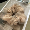 Detail view of champagne organza and satin oversized scrunchie on a stylish magazine - Champagne