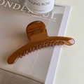 Detalle de pinza de pelo grande en color ámbar sobre una revista de moda - Marrón