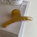 Primer plano de una pinza para el pelo grande de resina ámbar con textura brillante y muelle - Amarillo Mostaza
