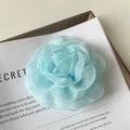 Gros plan d'une pince à cheveux camélia en organza bleu clair sur un plateau en bois - Bleu clair