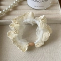 Dettaglio di un elastico in pizzo crema con bordi in rete e perla ovale marrone opaco - Bianco Sporco