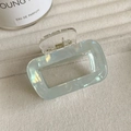 Gros plan d'une pince à cheveux carrée vert pâle irisé sur un tissu texturé doux - Vert Menthe