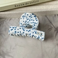 Detalle de pinza para el pelo de acetato con patrón jaspeado azul y letras doradas - Lunares azules
