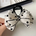 Detailed view of white polka dot silk bow hair claw clip with dark grey center gemstone - Beige Polka Dot