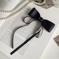 Detalle de lazo de satén negro con cintas largas sobre un libro antiguo con perlas - Negro