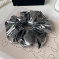 Detailaufnahme von silbernem Metallic-Haargummi mit Markenetikett und Falten - Silber Geflochtenes Leder Design