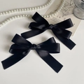 Détail de deux barrettes à nœuds en satin noir avec une texture soyeuse élégante - Noir