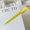 Detail of bright yellow metal hair clip with decorative holes on a white card - Lemon Yellow