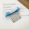 Vue détaillée du peigne à cheveux à 8 dents avec un nœud papillon en satin bleu clair - Bleu Satin
