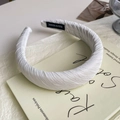 Dettaglio di un cerchietto bianco spesso in raso plissettato su un libro con etichetta a mano - Bianco Spigato