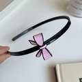 Dettaglio dell'elegante cerchietto con fiocco rosa e bordo nero su base in resina - Fiocco Rosa