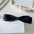 Dettaglio elegante fiocco in raso nero con perle su un vassoio bianco da esposizione - Stile Fiocco Sovrapposto