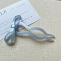 Macro detail of sky blue bow-shaped hair pin with streamlined wavy resin design - Light Blue