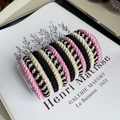 Detailed view of woven hair ties in four colors displayed on a clear vertical stand - Black Beige Pink