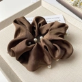 Dettaglio di un elastico in raso marrone con eleganti perle bianche su un vassoio display - Marrone Scuro