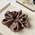 Dettaglio dell'elastico in raso marrone con perle su un vassoio decorativo chic - Marrone
