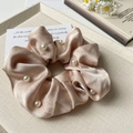 Dettaglio di un elegante elastico in seta satinata champagne con perle su un vassoio - Champagne