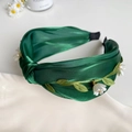 Détail d'un serre-tête en satin vert foncé avec broderie de feuilles et fleurs blanches - Vert