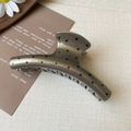 Detailed macro view of large dark grey hair claw clip with black polka dots and metallic finish - Brown Polka Dot Arc