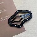 Dettaglio del fermaglio per capelli in pelle nera a pois bianchi con cuciture ondulate - Stile Nuvola Nera