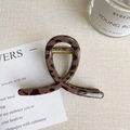 Detail of a large leopard print hair claw clip with a twisted design on a neutral desk - Dark Leopard - Small Bar Clip