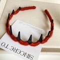 Detail of red yarn-wrapped headband with black demon spikes and anti-slip comb teeth - Red