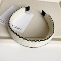 Detail eines weißen Woll-Haarreifens mit schwarzen Wellenstickereien und Textur - Beige