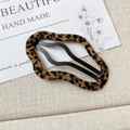 Detailansicht der Haarspange mit Leopardenmuster-Stoff und gewellter schwarzer Metallstruktur - Wolkenform Leopardenmuster