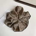 Close-up of leopard print satin scrunchie with elegant black edge detailing and texture - Brown