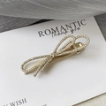 Dettaglio di un fermaglio a fiocco dorato con strass scintillanti su un biglietto bianco - Oro - Stile Fiocco