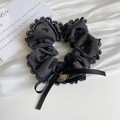 Detail eines dunkelgrauen Scrunchie mit schwarzer Spitze und gestickten Schleifen - Graues Haargummi
